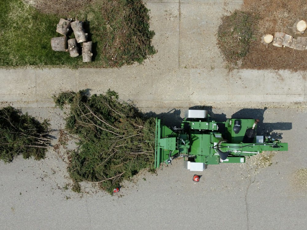 Crew feeding branches into a wood chipper on a residential street